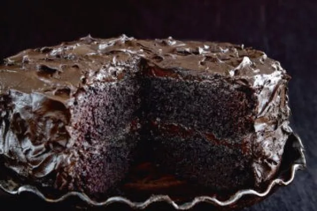 en saftig choklatårta med chokladfrosting på ett tårtfat med fot