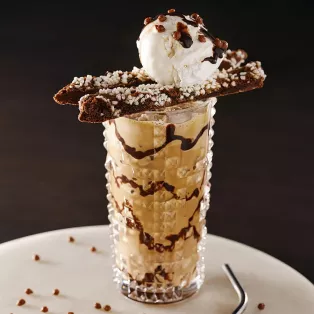 Ett glas med espresso milkshake med glass och chokladsås. Foto.
